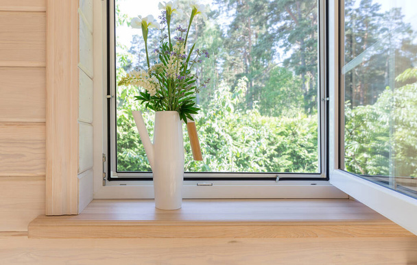 Finestra bianca con zanzariera in una rustica casa in legno con vista sul giardino. Bouquet di iris bianchi e lupini in annaffiatoio sul davanzale - Foto, immagini