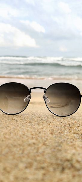 Sun glasses at the sand of the beach near the sea in india - 写真・画像