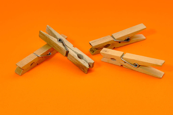 Conjunto de pinzas de madera que aparecen una por una sobre un fondo naranja. - Foto, imagen