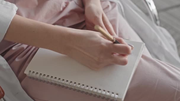 Από-πάνω γκρο πλαν με αργό ρυθμό αγνώριστη γυναίκα γιατρός κρατώντας σημειώσεις σε copybook γράφοντας αριθμούς ένα προς ένα - Πλάνα, βίντεο