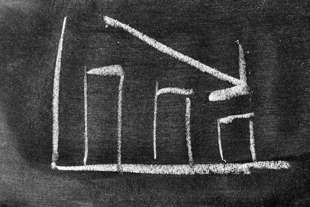 Білий крейдяний малюнок у формі стрілки на фоні дошки або крейди (концепція зменшення запасів, тенденція розвитку бізнесу, економіка
) - Фото, зображення
