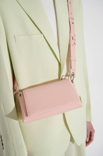 Ragazza in giacca verde chiaro con borsetta rosa cuoio. Look alla moda alla moda. Foto verticale. Donna d'affari moderna. - Foto, immagini