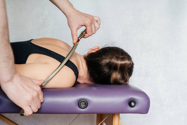 IASTM лечение миофасциального ограничения, женщина, получающая лечение мягких тканей на шее с инструментом IASTM из нержавеющей стали - Фото, изображение