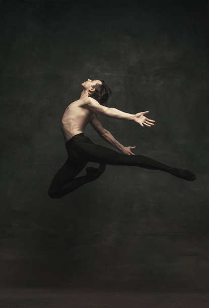 Junge und anmutige männliche Balletttänzerin isoliert auf dunklem Hintergrund. Kunst, Aktion, Inspirationskonzept. - Foto, Bild