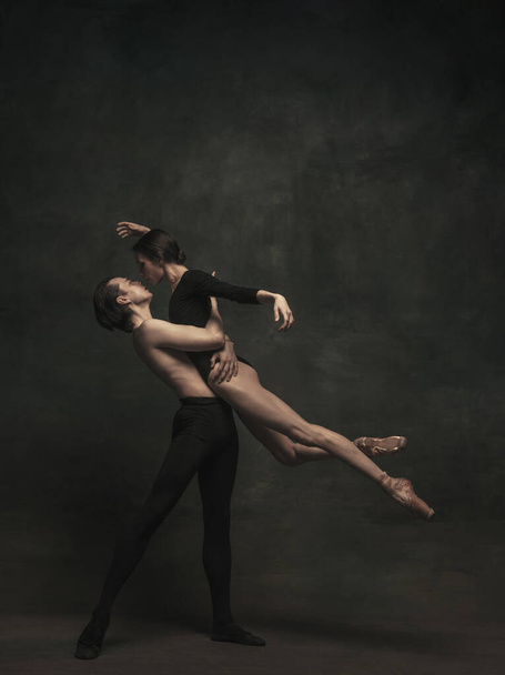 Beautiful graceful woman and man, ballet dancers in art performance dancing isolated over dark background - Photo, Image