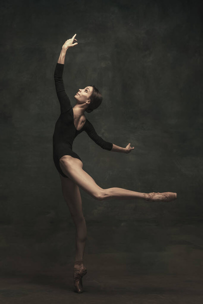 Joven y elegante bailarina de ballet aislada sobre fondo oscuro. Arte, movimiento, acción, flexibilidad, concepto de inspiración. - Foto, Imagen