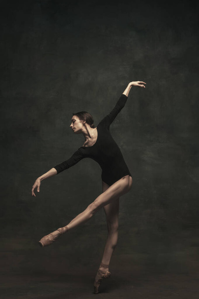 Fiatal és kecses balett táncos, sötét háttérrel. Művészet, mozgás, cselekvés, rugalmasság, inspiráció. - Fotó, kép