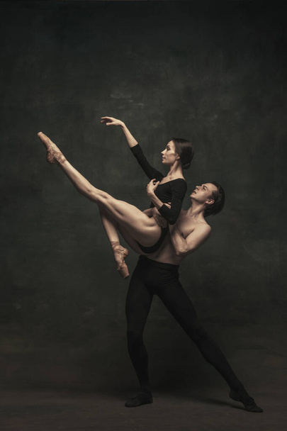 Piękna, pełna wdzięku kobieta i mężczyzna, tancerze baletowi w przedstawieniu artystycznym tańczący na ciemnym tle - Zdjęcie, obraz