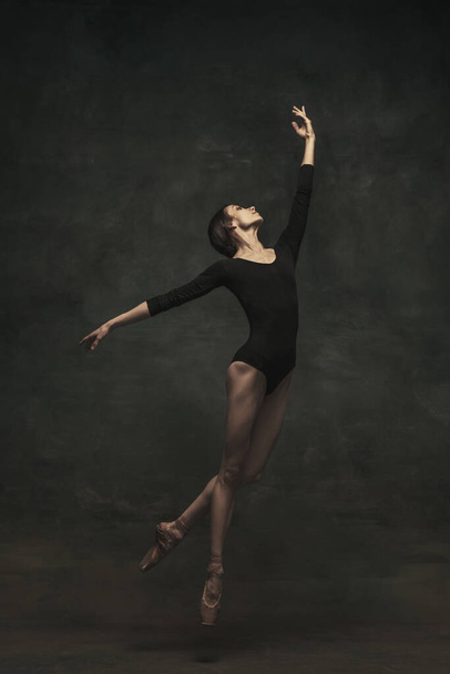 Fiatal és kecses balett táncos, sötét háttérrel. Művészet, mozgás, cselekvés, rugalmasság, inspiráció. - Fotó, kép