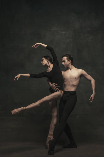 Hermosa mujer elegante y hombre, bailarines de ballet en performance de arte bailando aislados sobre fondo oscuro - Foto, imagen