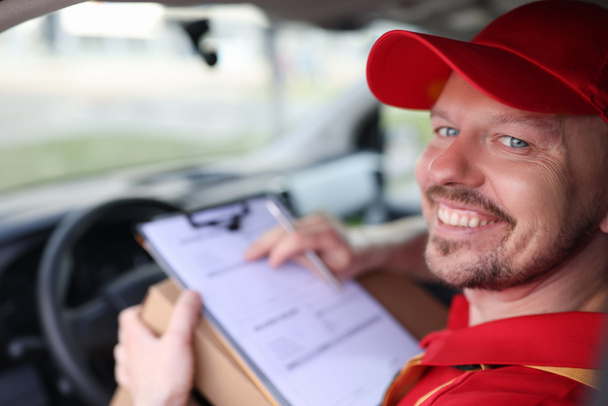 Retrato del conductor de mensajería masculino sonriente en el salón de automóviles con documentos - Foto, Imagen