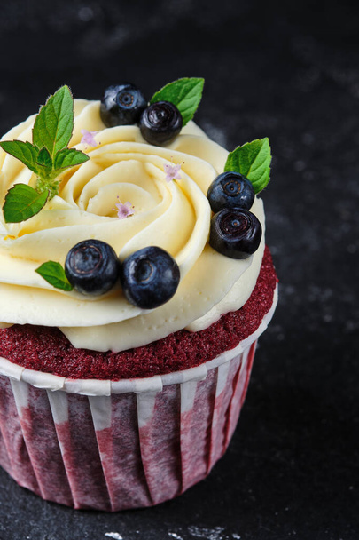 Red velvet cupcakes with cream cheese cream. Dessert garnished with fresh blueberries and mint. - Fotografie, Obrázek