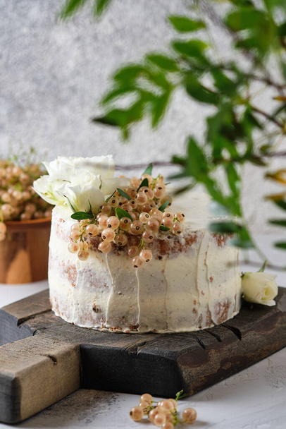 Homemade sponge cake with cream cheese cream and white currant filling. Festive dessert decorated with flowers. - Photo, image