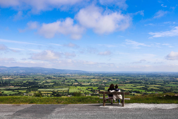 2人の友人は、アイルランドのClogheen郡のTipperaryのKnockmealdown山のVee Passの道路の端近くのベンチに座っています - 写真・画像