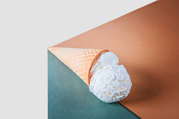 Ice cream in a waffle cone lies on craft paper. - 写真・画像