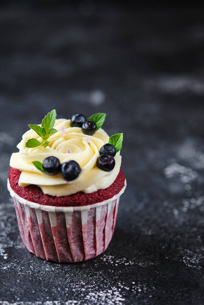 Red velvet cupcakes with cream cheese cream. Dessert garnished with fresh blueberries and mint. - 写真・画像