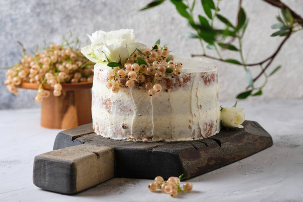 Homemade sponge cake with cream cheese cream and white currant filling. Festive dessert decorated with flowers. - Photo, image