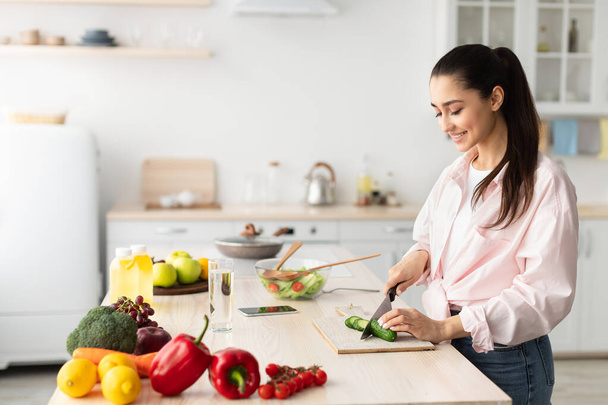 Portrait of smiling young lady cooking fresh salad - Photo, image