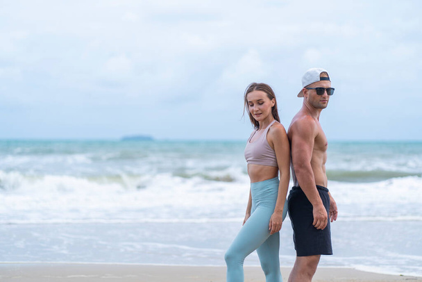 Νεαρά ζευγάρια στέκονται μπρος-πίσω μετά την άσκηση μαζί στην παραλία  - Φωτογραφία, εικόνα