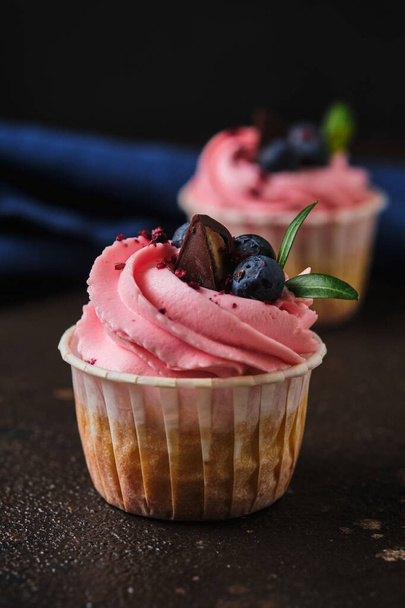 Pasteles para amantes y rosas. Cupcakes con crema de queso crema rosa, decorado con bayas, hierbas y chocolate. - Foto, imagen
