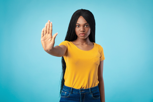 Eltökélt afro-amerikai nő Gesturing Stop To Camera, kék háttér - Fotó, kép