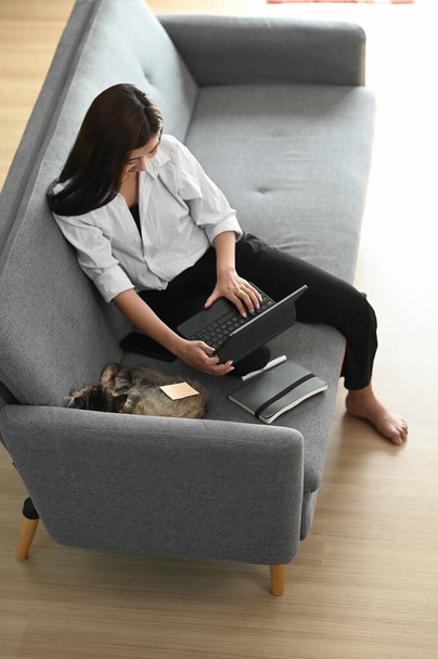 Plan sur la tête d'une jeune femme heureuse assise sur un canapé et utilisant une tablette dans le salon. - Photo, image