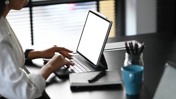 Cropped shot of young female typing on blank screen tablet in her workspace. - Fotoğraf, Görsel