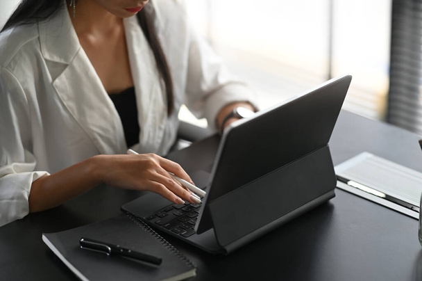 Colpo ritagliato di giovane penna stilo femminile mentre si lavora su tablet computer nel suo spazio di lavoro. - Foto, immagini
