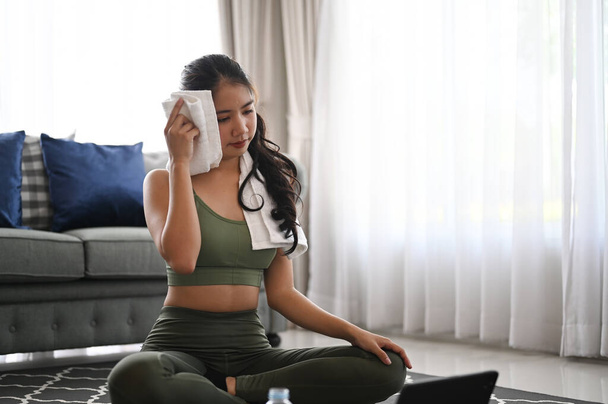Asian beauty woman in sport bra wiping sweat with towel after workout at home. - Photo, Image