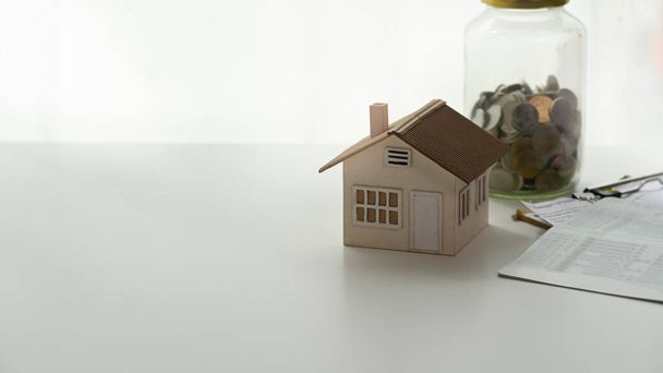 Επενδυτικά ακίνητα χρήματα και σπίτι ιδιόκτητο μοντέλο σπίτι παιχνίδι σε λευκό τραπέζι. - Φωτογραφία, εικόνα