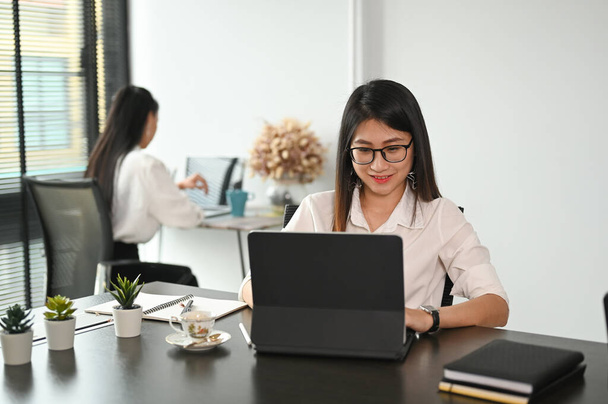 オフィスで働くためにタブレットコンピュータを使用して幸せな若い女性. - 写真・画像
