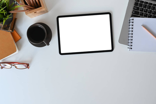 Дизайнерський робочий планшет з білим екраном, зошитом, канцелярським приладдям та чашкою кави для відображення графіки
. - Фото, зображення