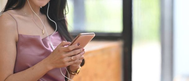 Young woman girl using smartphone earphones listening to music or having fun watching video. - Photo, image
