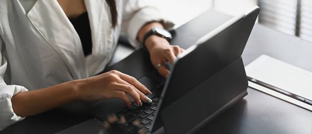 Ujęcie bizneswoman pracującej z tabletem komputerowym na czarnym drewnianym stole w nowoczesnym biurze. - Zdjęcie, obraz