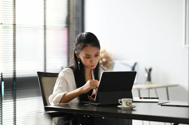 Una donna d'affari che utilizza tablet tramite tecnologia internet wireless che lavora online in ufficio. - Foto, immagini