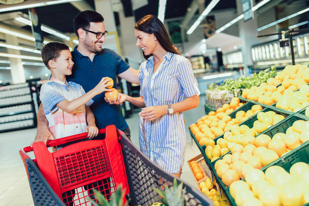 Felice famiglia che acquista frutta al supermercato o negozio di alimentari - shopping, cibo, vendita, consumismo - Foto, immagini
