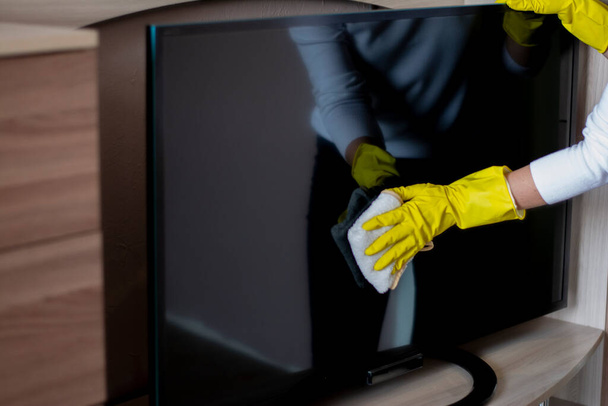 Close-up hand in protective gloves wipes the rag TV display - Φωτογραφία, εικόνα