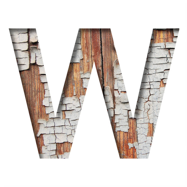 Vintage backdrop font.The letter W cut out of paper against the background of an old wooden wall with cracked paint. Decorative alphabet on an old surface. - Zdjęcie, obraz