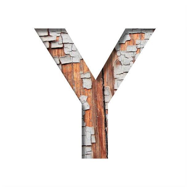 Vintage backdrop font.The letter Y cut out of paper against the background of an old wooden wall with cracked paint. Decorative alphabet on an old surface. - 写真・画像