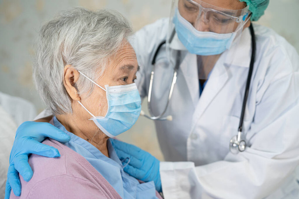 医師チェックアジアのシニアまたは高齢女性患者感染症を保護するために病院で顔マスクを着用Covid-19コロナウイルス. - 写真・画像