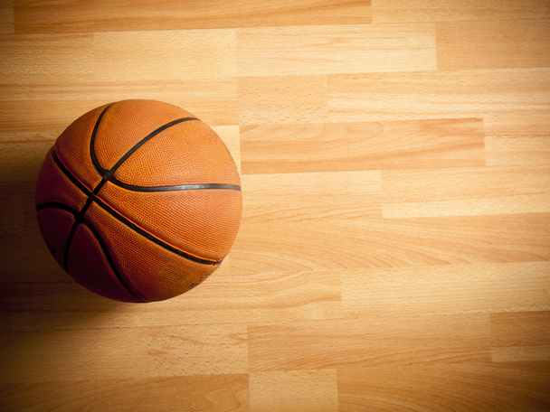 Μια επίσημη πορτοκαλί μπάλα σε ένα γήπεδο μπάσκετ σκληρού ξύλου  - Φωτογραφία, εικόνα