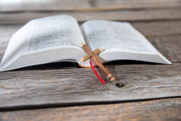 wooden cross on the open Bible on tabl - Foto, afbeelding