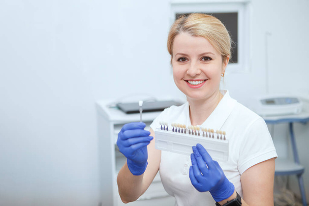 Charmante femme dentiste souriant à la caméra, tenant dents tableau d'ombrage blanchissant, espace de copie - Photo, image