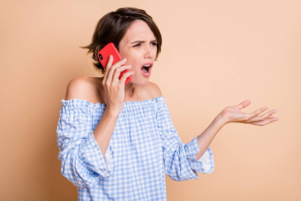 Photo portrait of confused girl not understanding hearing talking on phone isolated on pastel beige colored background - Foto, Bild