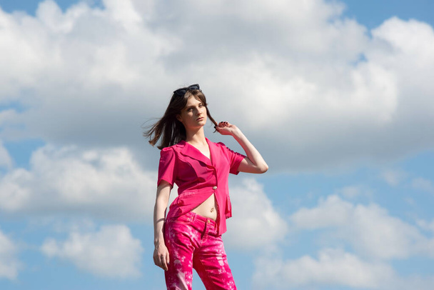πορτρέτο ενός μοντέρνου κοριτσιού σε ροζ χρώμα ενάντια στον ουρανό. - Φωτογραφία, εικόνα