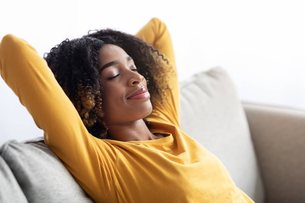 Retrato de calma jovem mulher negra descansando no sofá confortável em casa - Foto, Imagem