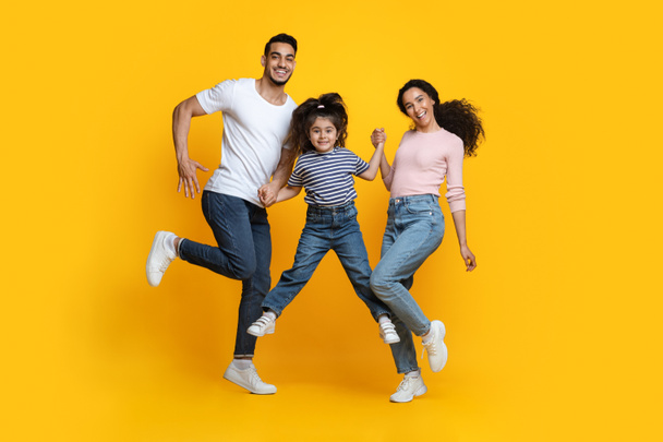 Cheerful Middle Eastern Family Of Three Holding Hands While Jumping In Air - Photo, Image