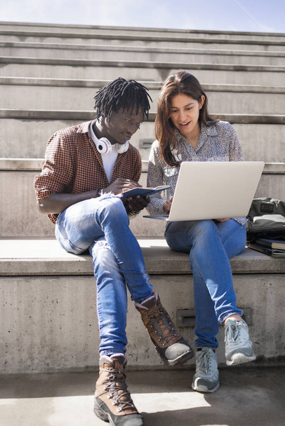 Багатонаціональні команди в університеті. Африканський чоловік і латинська жінка студенти, які працюють разом з ноутбуком - Фото, зображення