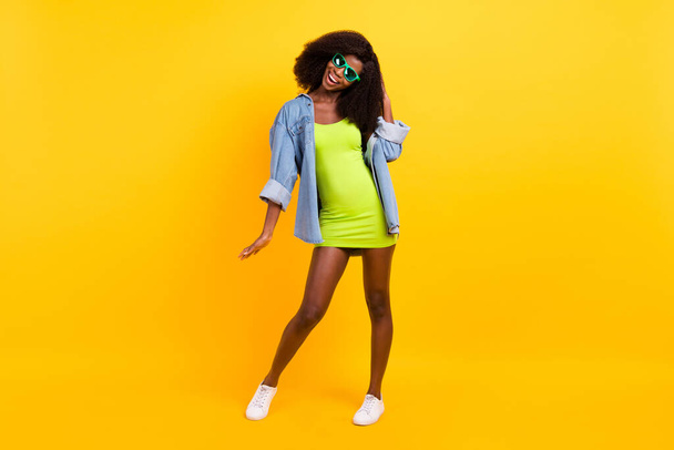 Full length body size photo of girl in green dress wearing sunglass dancing overjoyed isolated vibrant yellow color background - Fotó, kép