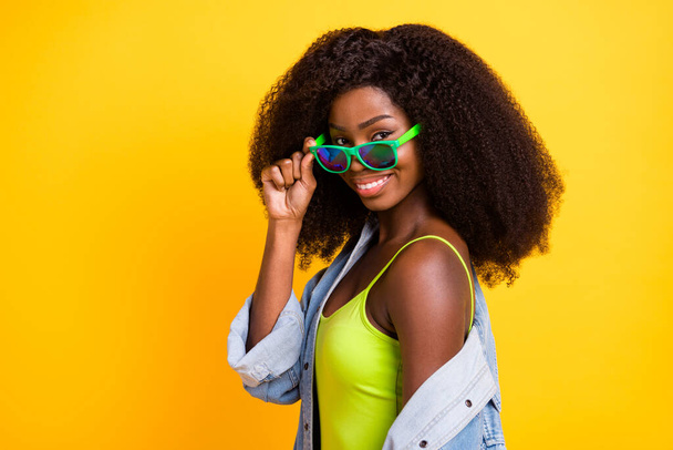 Photo portrait of young woman smiling taking-off sunglass curly hairstyle spending free time isolated vivid yellow color background - Fotó, kép